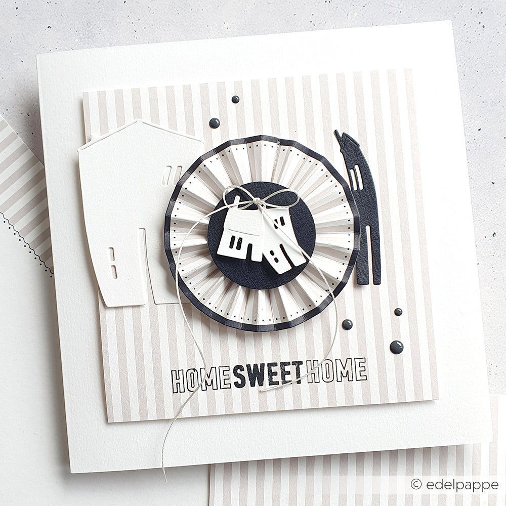 Handgemachte Karte von Alexandra Renke mit geschichteten Papierhäusern, dem Text "Home Sweet Home", einem neutral gestreiften Hintergrund und detaillierten Akzenten, die mit einem Photopolymer-Stempel erstellt wurden.
