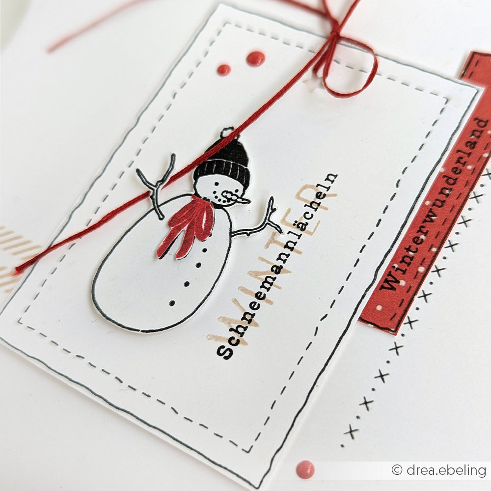 Eine handgefertigte Karte von Alexandra Renke mit Schneemotiven - einem Schneemann, einer roten Schnur und den deutschen Wörtern "Schneemannlächeln" und "Winter-Wunderland" - hergestellt mit Photopolymer-Klarsichtstempeln für scharfe Details.