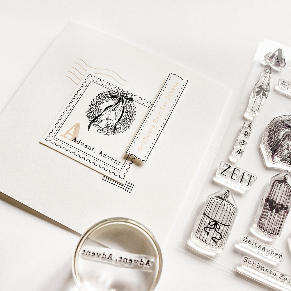 Eine handgefertigte Karte mit Adventsmotiven von Alexandra Renke mit einem Kranzstempel, Photopolymer-Klarsichtstempeln und einem runden "Advent, Advent"-Stempel auf einer weißen Fläche.