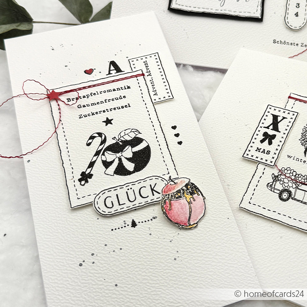 Handgemachte Weihnachtskarte von Alexandra Renke mit festlichen Illustrationen, roter Kordel und deutschem Text auf weißem Strukturpapier mit einem einzigartigen Komposition Bratapfel Design, das mit der Premium Clear Stamp Technik hergestellt wurde.
