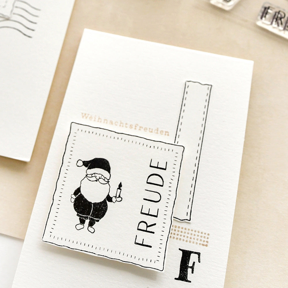 Eine Weihnachtskarte mit einem photopolymeren Santa-Klarsichtstempel von Alexandra Renke, dem Wort "FREUDE" und dem deutschen Text "Weihnachtsfreuden" darüber.