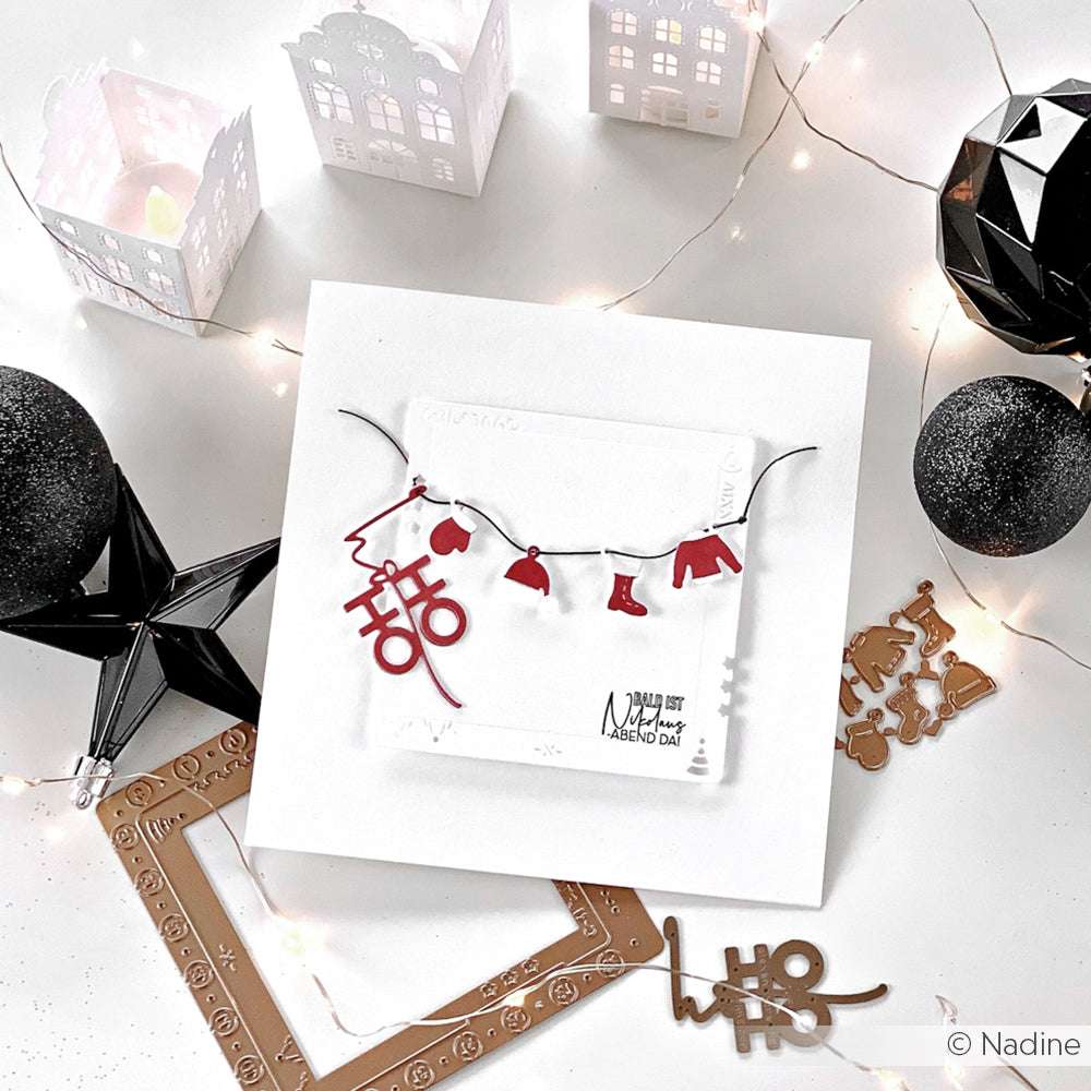 Handgefertigte Weihnachtskarte von Alexandra Renke mit einer roten Mini-Kleidergirlande, hergestellt mit Designpapieren und der Motivstanze Mini-Wintergarderobe, umgeben von festlichem Dekor und Lichterketten.