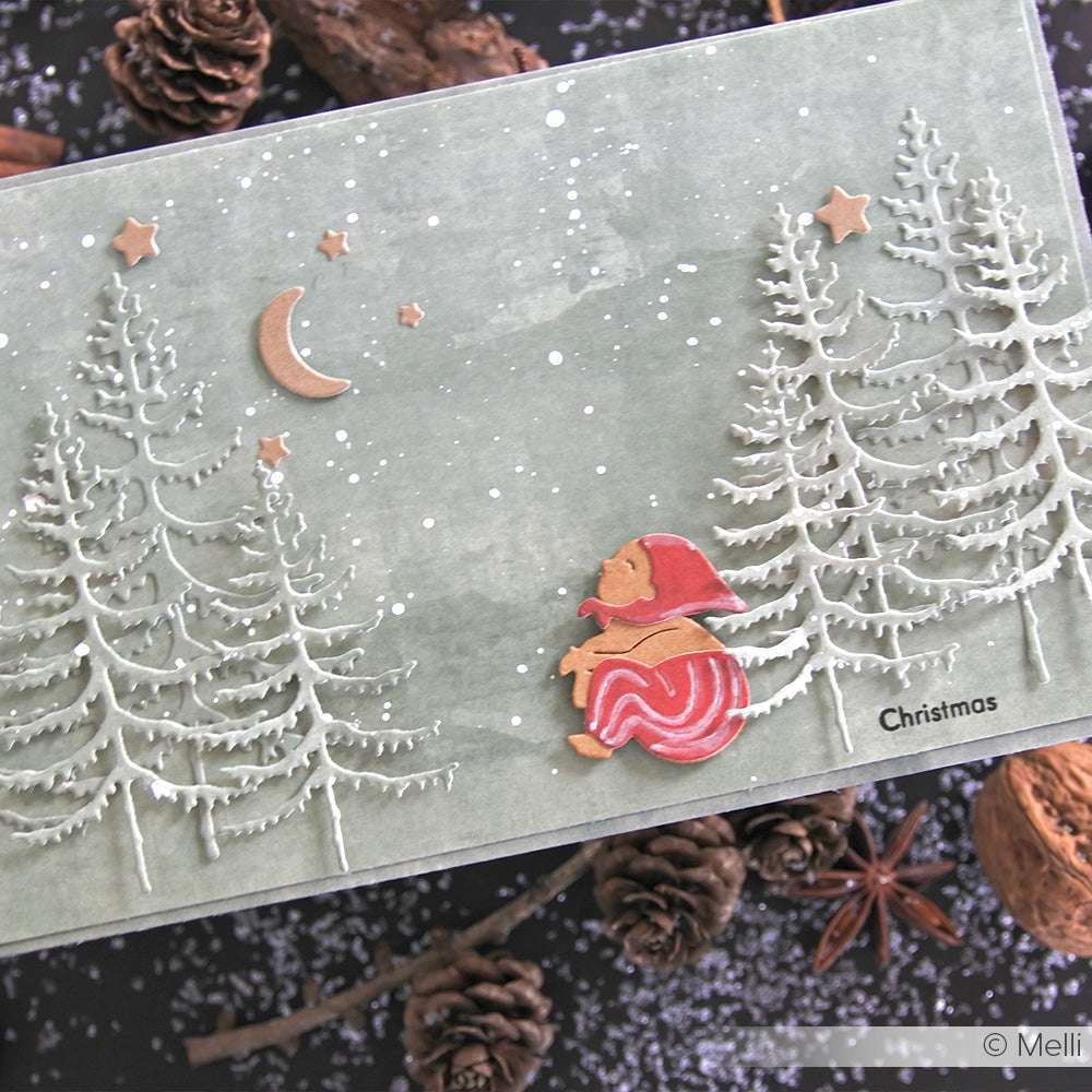 Handgefertigte Weihnachtskarte mit einem Wichtel mit roter Mütze, verschneiten Bäumen, Sternen und einer Mondsichel auf grauem Grund - hergestellt mit Alexandra Renke Stanzformen für gestochen scharfe, bezaubernde Details unter Verwendung hochwertiger Materialien.