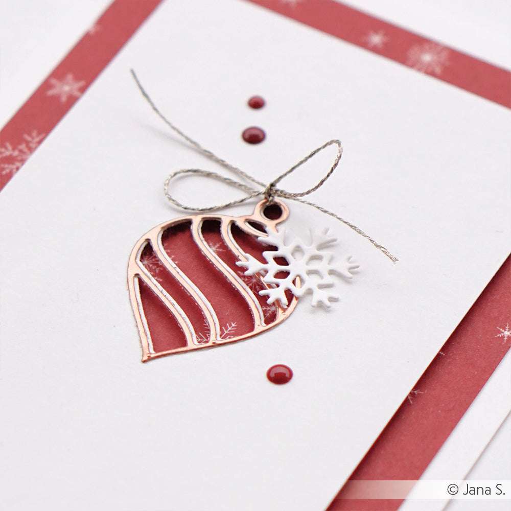 Eine handgefertigte Weihnachtskarte von Alexandra Renke, gestaltet mit Designpapier und verziert mit einer Metallkugel (Motivstanze Baumkugel), Schneeflocke, Schleife und roten Punkten auf weißem und rotem Papier.