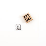 Ein Holzstempel mit der Abbildung eines Rentiers in einem Briefmarkenrahmen sowie ein Stempelabdruck desselben Holzstempel-Motivs.
