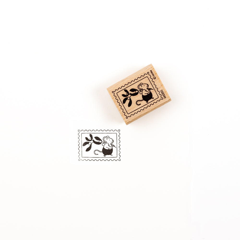 Ein Holzstempel und sein Abdruck, der eine Maus zeigt, die einen Mistelzweig in einem Briefmarkenrahmen hält.