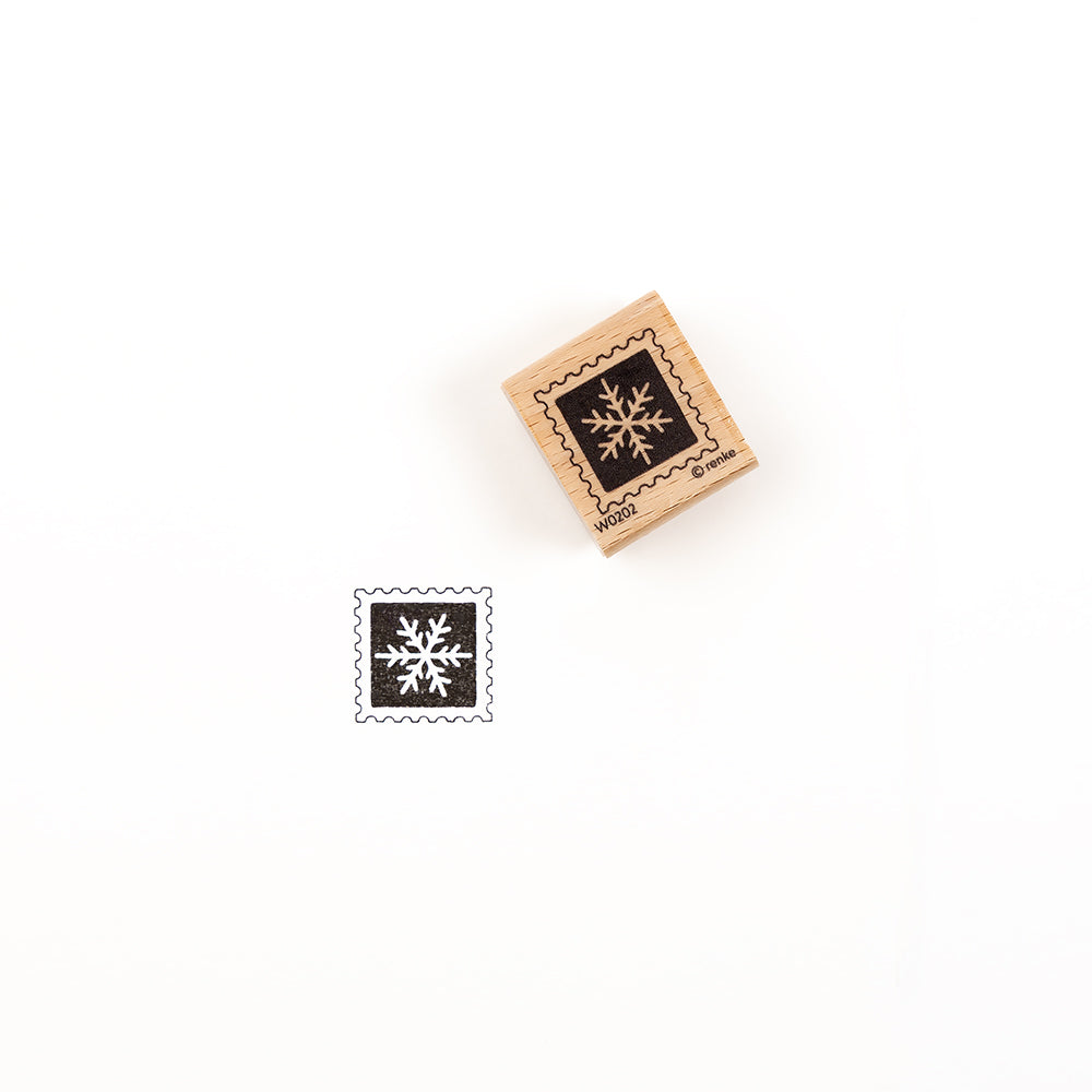 Ein quadratischer Holzstempel mit einem Schneeflockenmotiv und dem dazugehörigen Abdruck in schwarzer Tinte, der den Holzstempel zeigt.