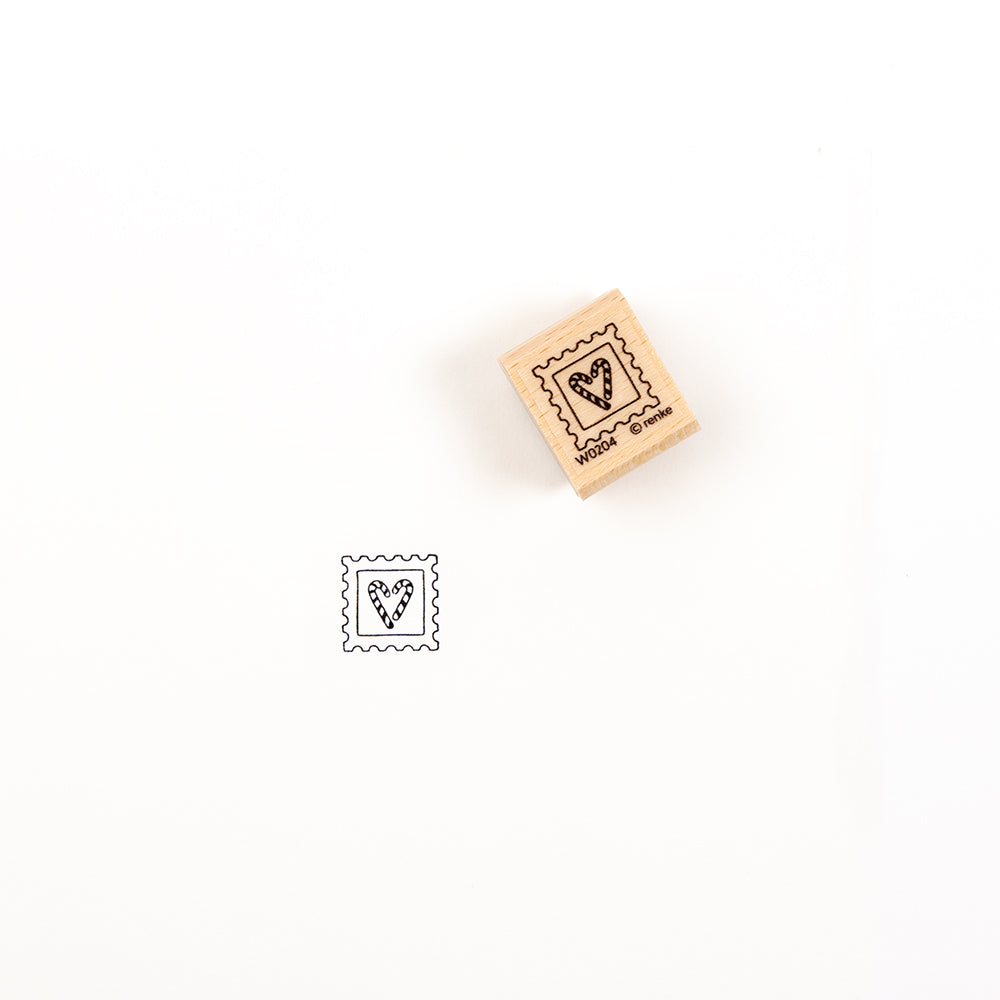 Ein Holzstempel mit einem Zuckerstangen-Herz-Motiv und dem dazugehörigen Stempelgummi-Stempel darunter.
