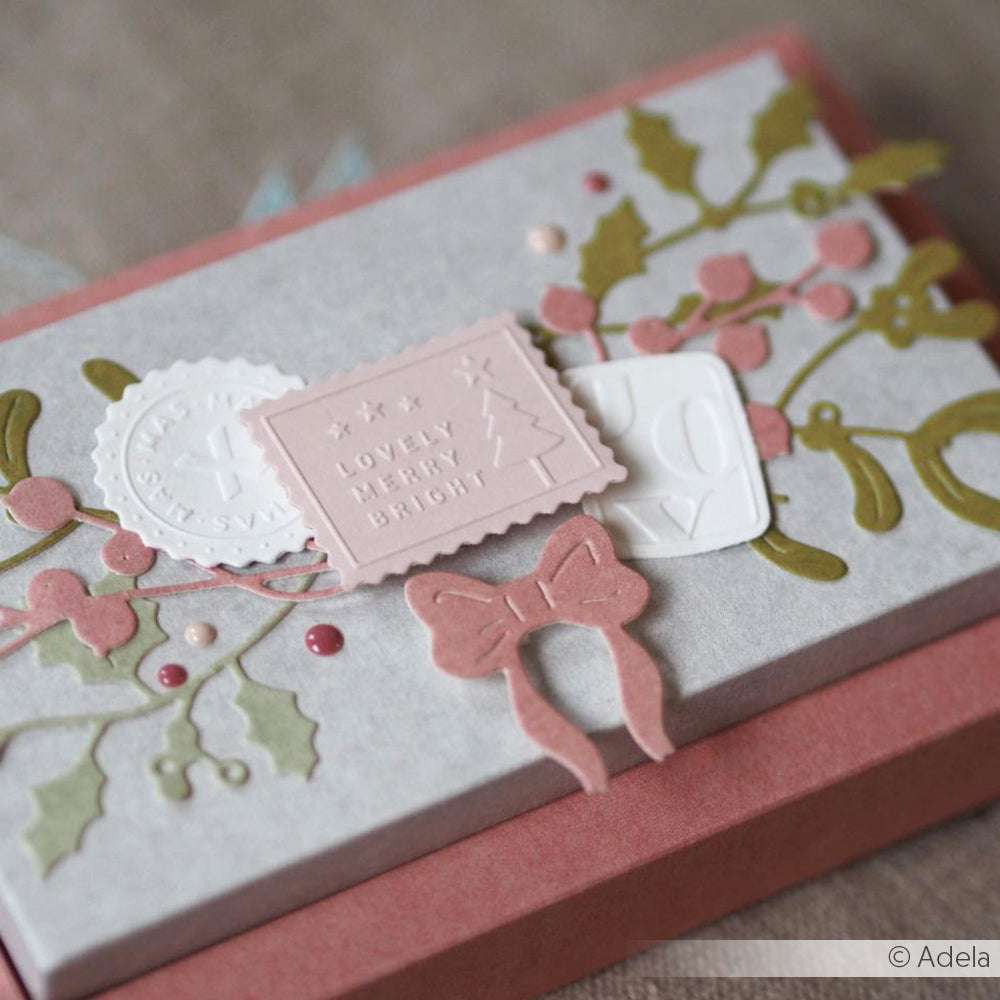 Eine dekorative Geschenkschachtel mit festlichen Anhängern, Grünzeug, Beeren und einer rosa Papierschleife, die mit Alexandra Renke Designpapieren und der Motivstanze Schleifen Quartett ausgestanzt wurde.