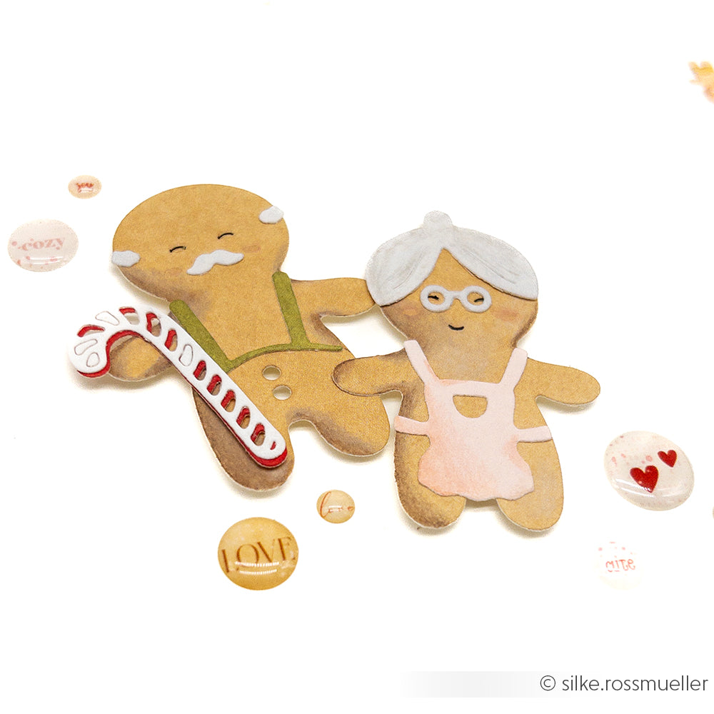Zwei Lebkuchen in Form eines älteren Mannes und einer älteren Frau, umgeben von festlichen Akzenten - gefertigt mit der Alexandra Renke Motivstanze Lebkuchen Großeltern, perfekt für charmante Stanzen für Designpapier-Projekte.