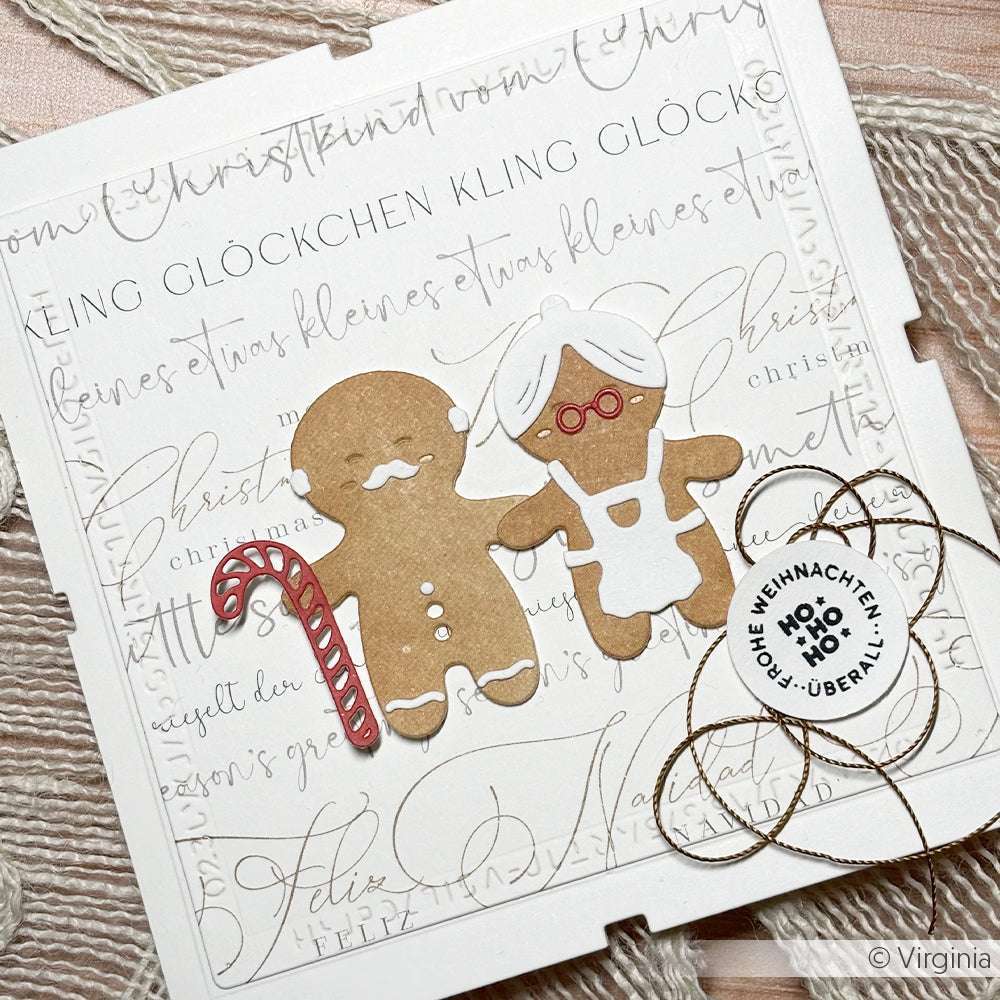 Handgemachte Weihnachtskarte von Alexandra Renke mit DieCut Systeme Lebkuchenmännchen, einer Zuckerstange und einem runden HO HO HO Anhänger auf festlichem Designpapier.