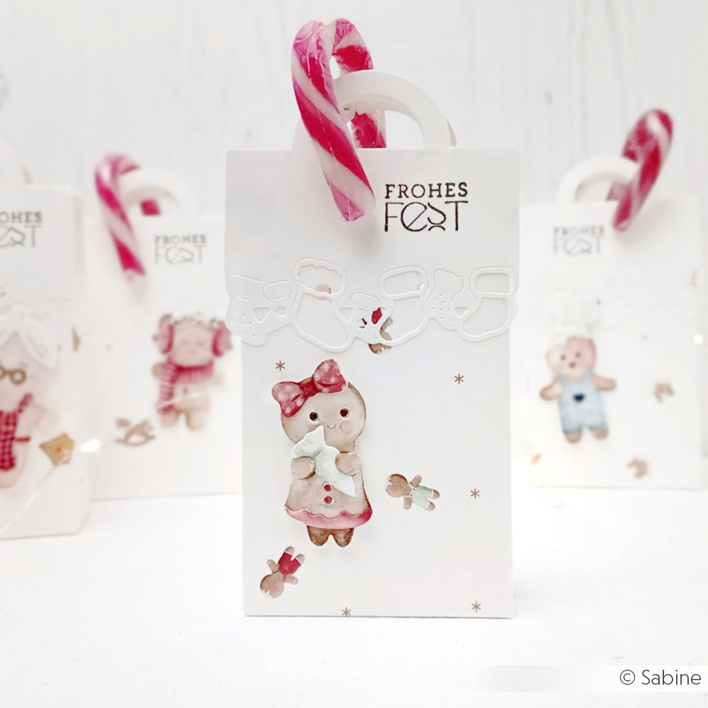 Eine festliche Geschenktüte von Alexandra Renke mit niedlicher Tierillustration, Zuckerstangenhenkel, Etikett "Frohes Fest", aus Designpapier und mit Akzenten aus der Motivstanze Lebkuchen-Kinder Bäckerei Kollektion.