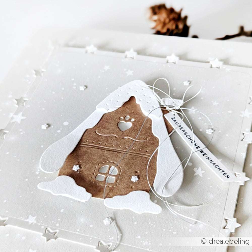 Eine handgefertigte Weihnachtskarte mit einem verschneiten Lebkuchenhaus, hergestellt mit Alexandra Renke Motivstanze Lebkuchenhäuschen und Designpapieren, versehen mit einem Anhänger mit der Aufschrift "Zauberschöne Weihnachten".