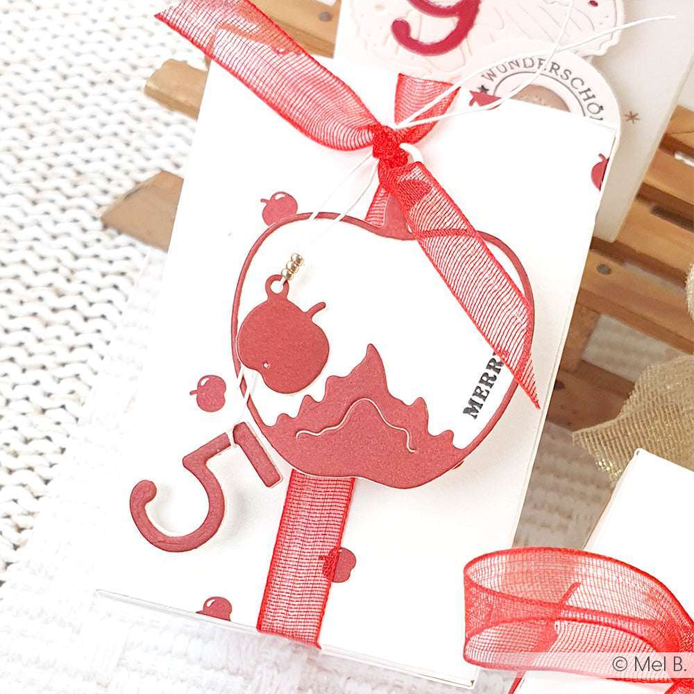 Weißer Geschenkkarton mit rotem Apfelausschnitt aus Alexandra Renke Motivstanze Bratapfel Rahmen, fröhlichem Text und roter Schleife; ideal für Designpapiere und kompatibel mit Alexandra Renke DieCut Systemen.