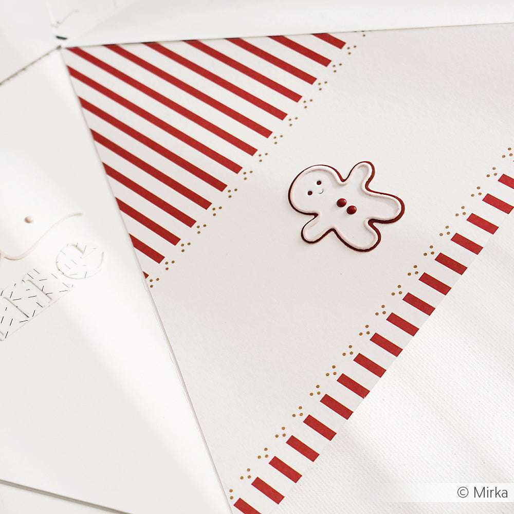 Weißer Umschlag mit roten Streifen und einem kleinen Lebkuchenmännchen, hergestellt mit Alexandra Renke Motivstanze Lebkuchenmännchen, ausgestellt auf einer weißen Fläche.
