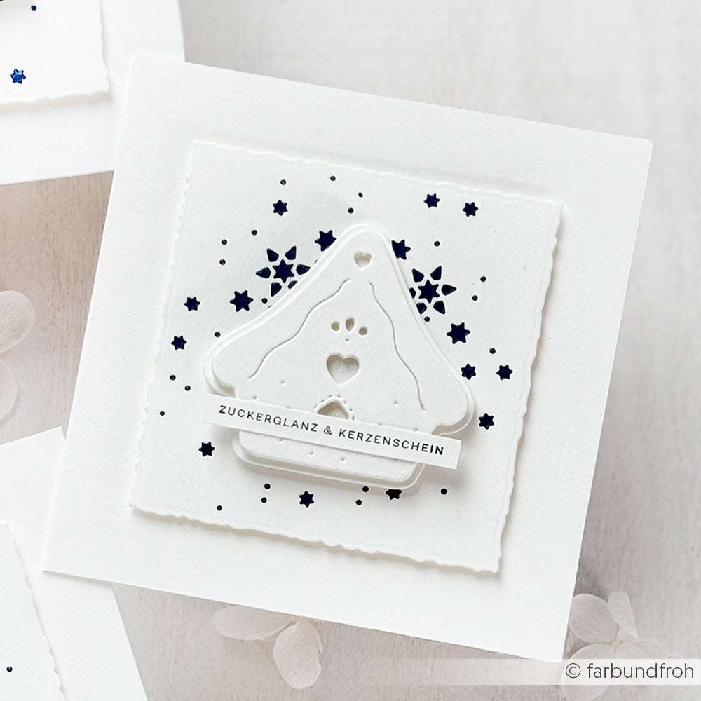 Weiße Weihnachtskarte von Alexandra Renke mit einem Hausschmuck aus Dies aus Stahl und Motivstanze Lebkuchenhaus, verziert mit einem navyfarbenen Sternmuster und dem Text "Zuckerglanz & Kerzenschein".