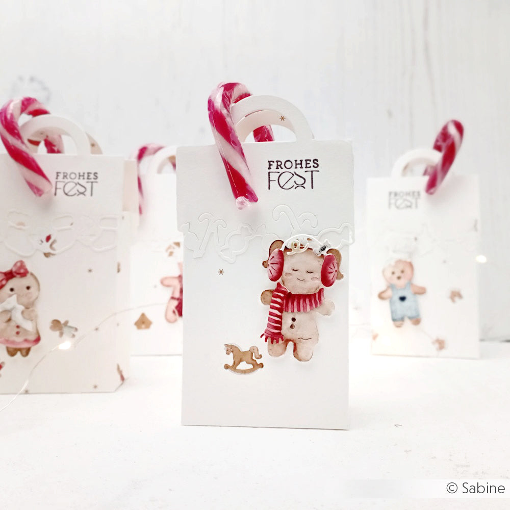 Weiße Geschenktüten mit niedlichen Bären- und Zuckerstangenmotiven von Alexandra Renke, arrangiert auf einer weißen Fläche - ideal zum Kombinieren mit Designpapieren oder zur Ergänzung mit DieCut Systemen für zusätzlichen Weihnachtszauber.