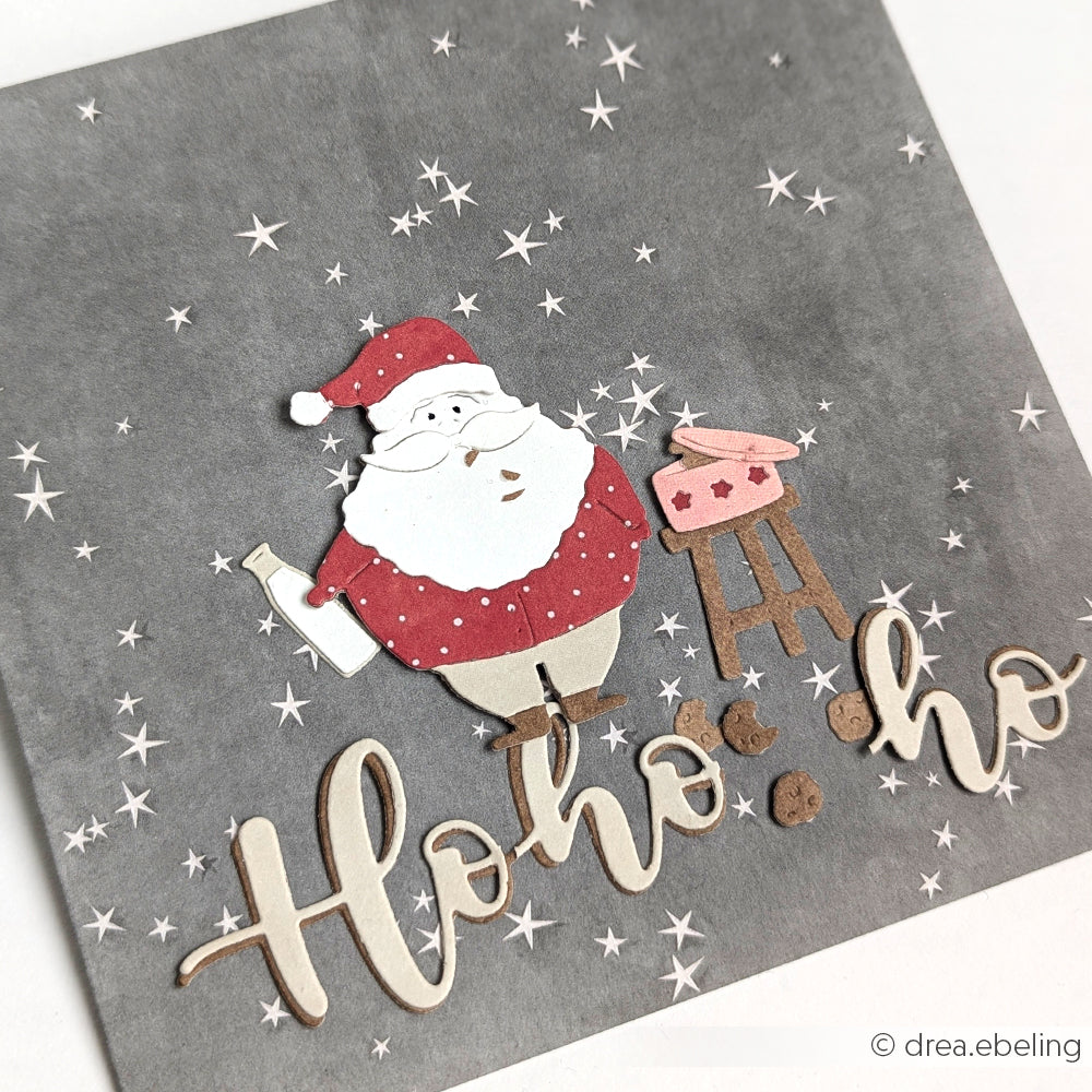Weihnachtsmann mit Grill und "Ho Ho Ho"-Text auf grauem Sternenhintergrund, mit festlichen Stanzdetails; Karte von Alexandra Renke.