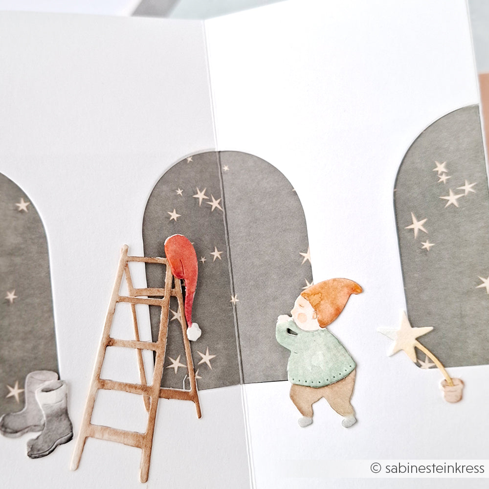 Handgefertigte Karte von Alexandra Renke mit Wichtel, Leiter, Stiefeln, Sternen und Weihnachtsmannmütze vor gewölbten grauen Fenstern, hergestellt mit Stanzsystemen Dies für detaillierte Akzente.