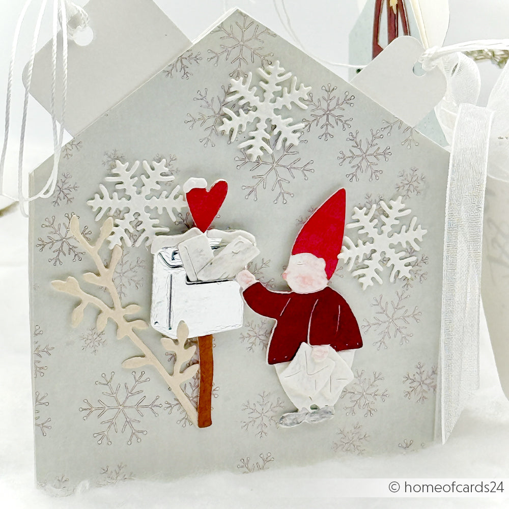 Ein Gnom mit roter Mütze wirft einen Brief in einen verschneiten Briefkasten auf dieser winterlichen Karte von Alexandra Renke - ideal, um Designpapiere oder den skurrilen Charme der Motivstanze Wichtel-Post Stanzsysteme zu unterstreichen.
