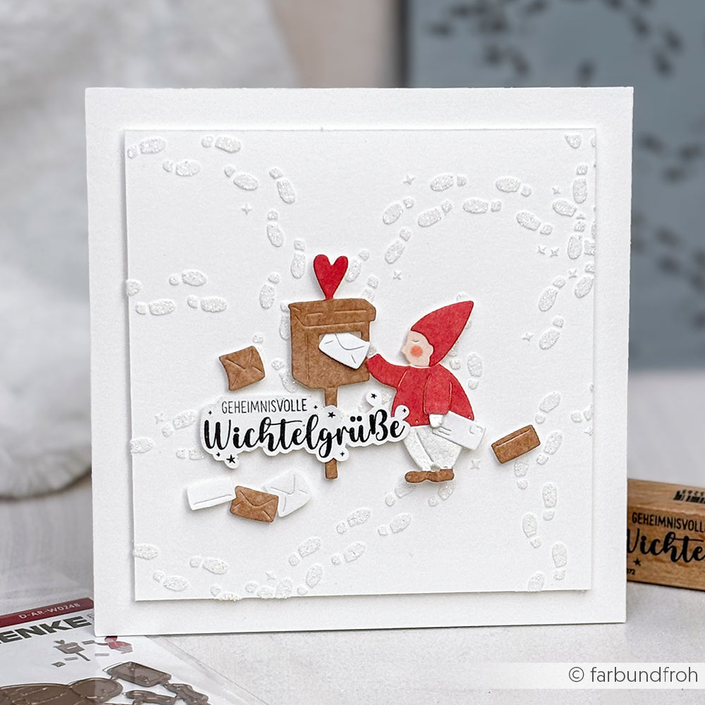 Die handgefertigte Karte von Alexandra Renke zeigt einen Gnom, der Briefe, Fußabdrücke und Umschläge vor einem verschneiten Hintergrund verschickt. Sie wurde mit der Motivstanze Wichtel-Post DieCut Systeme und den passenden Designpapieren hergestellt.