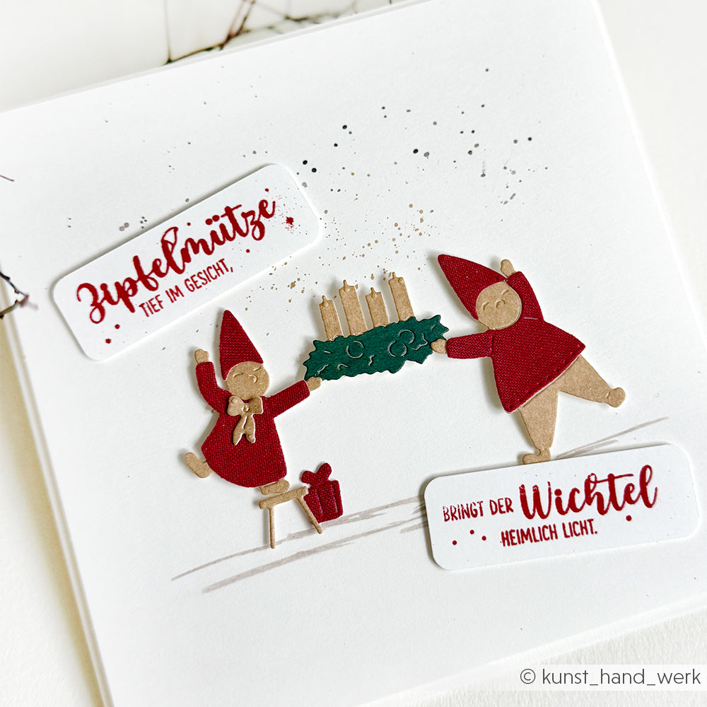 Zwei rot gekleidete Zwerge halten einen Kranz mit Kerzen; deutsche Weihnachtstexte zieren weiße Karten, die mit Alexandra Renke Designpapieren und der Motivstanze Advent-Wichtel Stanzsysteme festlich gestaltet sind.