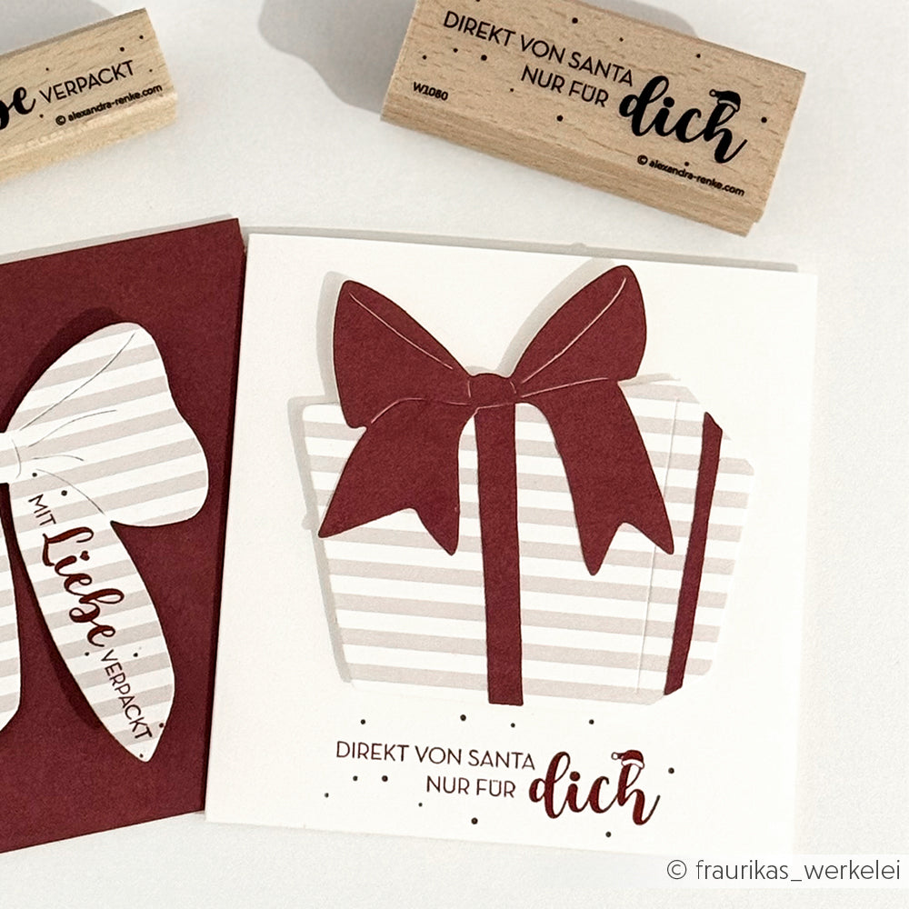 Handgefertigte Karte von Alexandra Renke mit einer gestreiften Geschenkbox mit roter Schleife und der Botschaft "Direkt von Santa nur für dich", hergestellt mit Stanzen für Designpapier für scharfe, festliche Kanten.