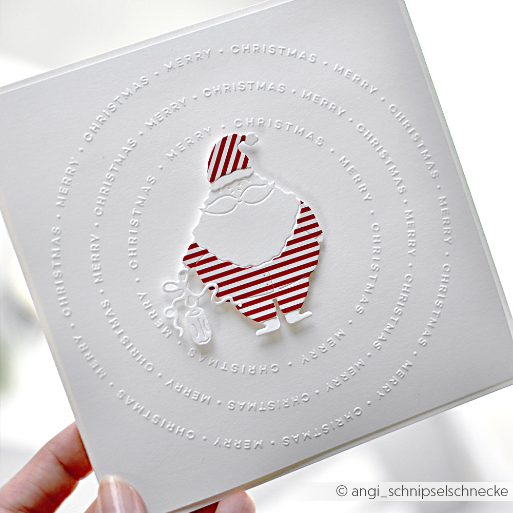 Weiße Karte von Alexandra Renke mit einem rot gestreiften Weihnachtsmann DieCut Systeme, der von einem kreisförmigen Text "Frohe Weihnachten" umgeben ist.