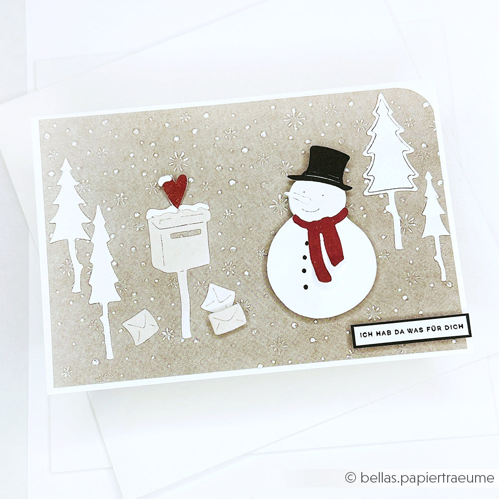 Handgefertigte Alexandra Renke Karte mit Schneemann, Bäumen, Briefkasten, Buchstaben und deutschem Text auf verschneitem beigem Designpapier.