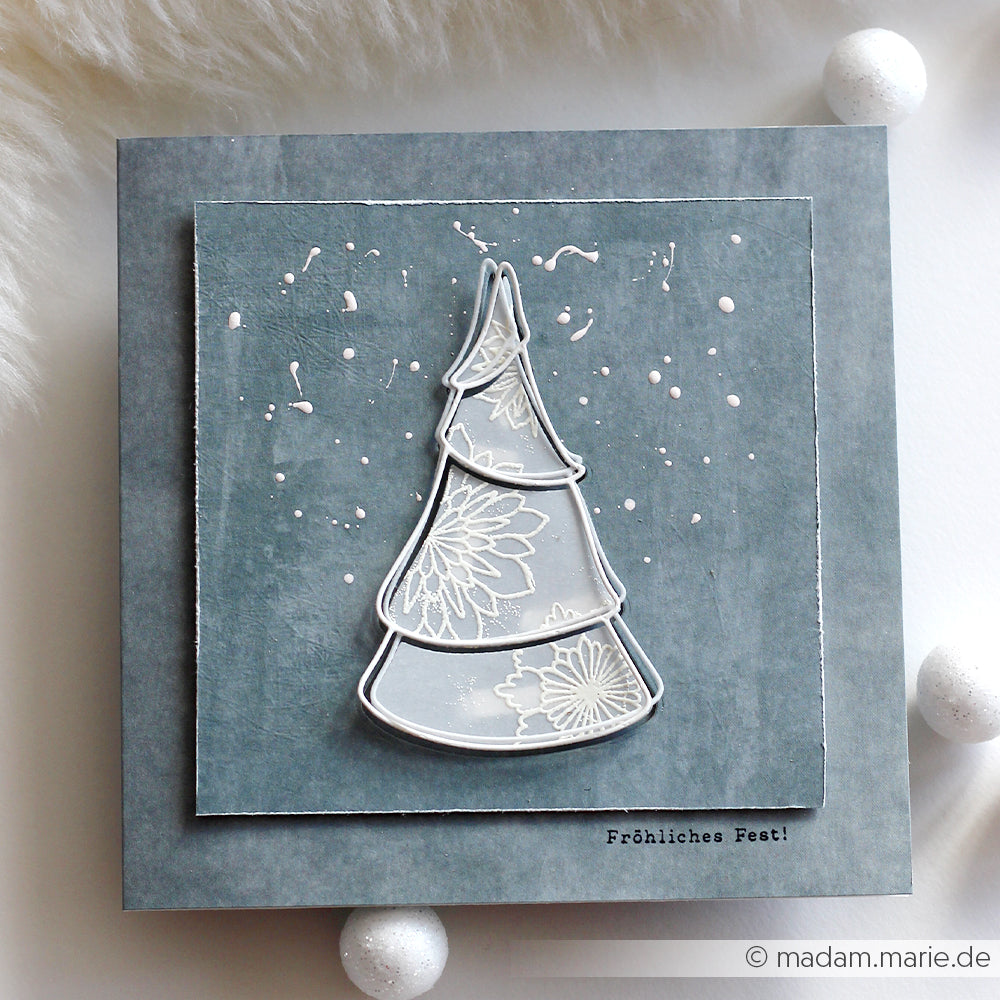 Handgefertigte Karte von Alexandra Renke mit einem weiß umrandeten Weihnachtsbaum (Motivstanze Tannenbaum) auf grauem Strukturpapier und der Aufschrift "Fröhliches Fest!".