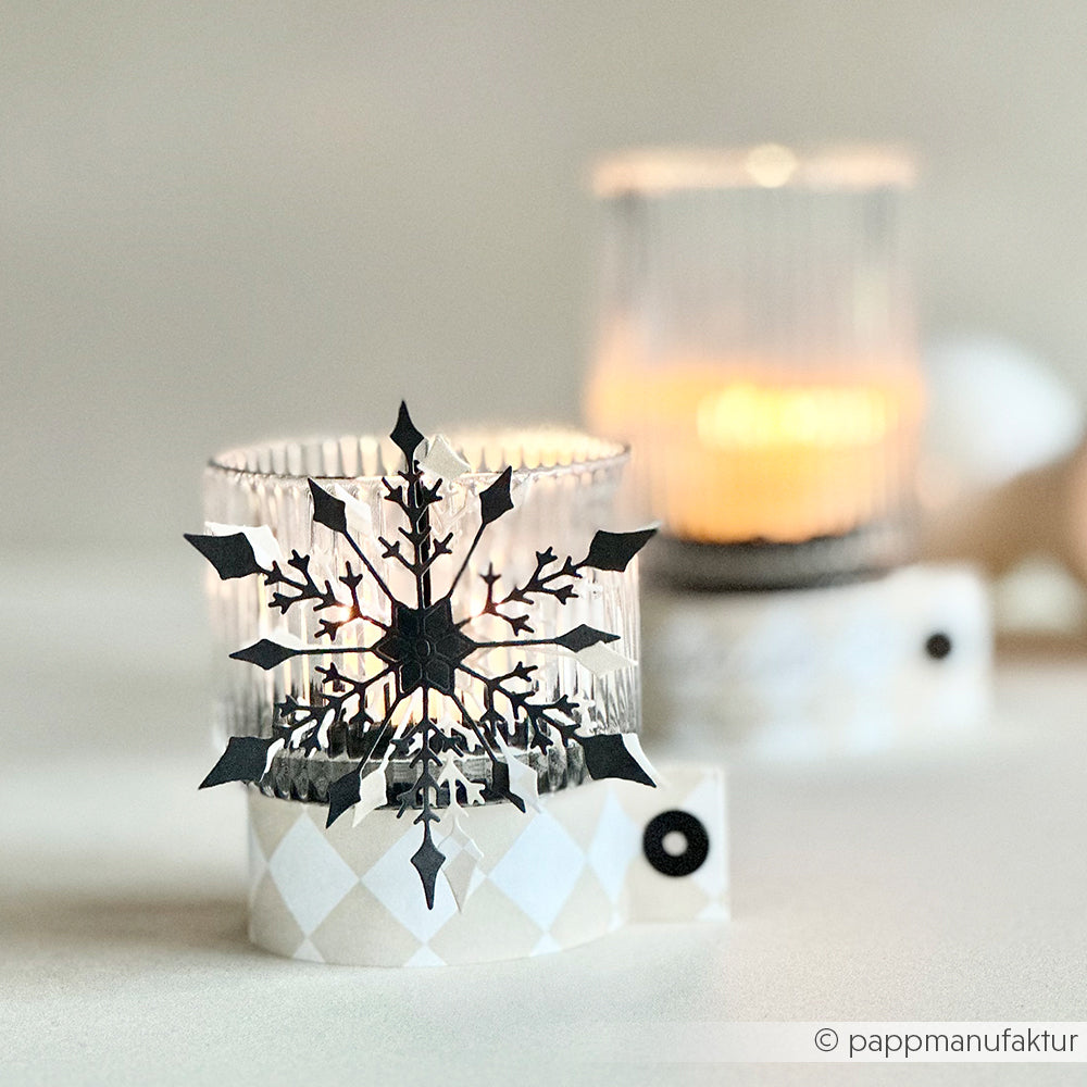 Zwei gläserne Kerzenhalter mit brennenden Kerzen, einer davon verziert mit einem schwarzen Schneeflockenausschnitt von Alexandra Renke aus der Motivstanze Große Schneeflocke Stanzsysteme.