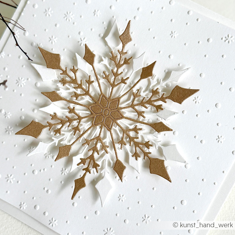 Goldene und weiße Schneeflocken-Schichtdekoration mit Alexandra Renke Designpapieren und der Motivstanze Große Schneeflocke auf strukturiertem, geprägtem weißen Hintergrund.