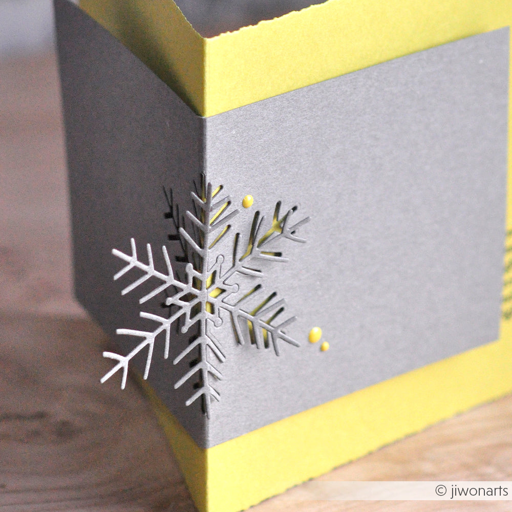 Graue und gelbe Karte mit ausgeschnittenem Schneeflockenmotiv auf der Vorderseite, hergestellt mit der Alexandra Renke Motivstanze Große Schneeflocke für elegante Ergebnisse beim Papierbasteln oder bei der Verwendung mit Stanzsystemen.
