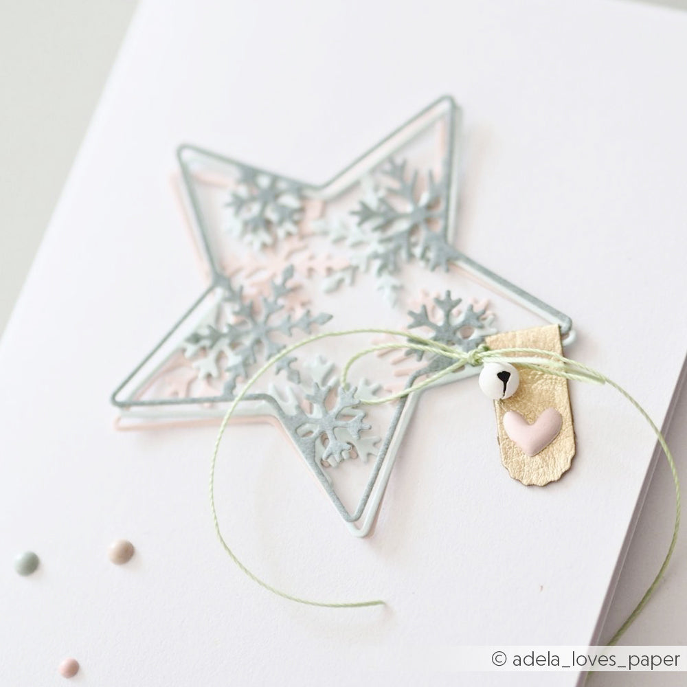 Handgefertigte Karte mit einer mehrschichtigen Motivstanze Schneeflockenstern, einem Glöckchen und einem Herz.