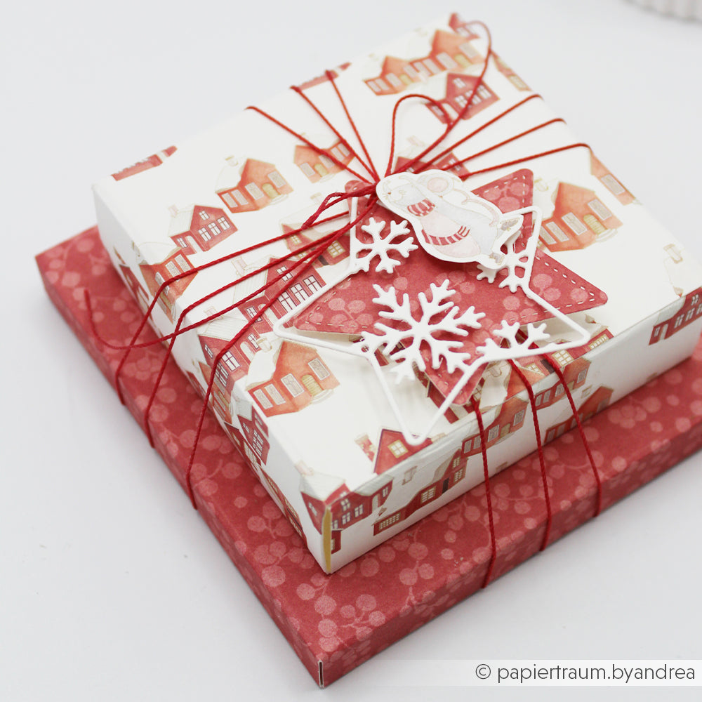 Zwei übereinander gestapelte Geschenkboxen aus festlichem Designpapier, verziert mit Schneeflocken-Ornamenten.