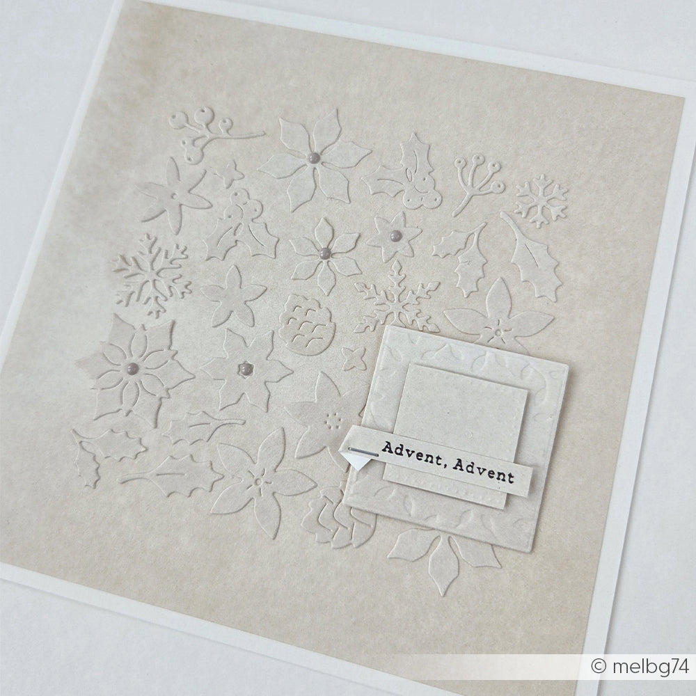 Quadratische Karte mit geprägten weihnachtlichen Pflanzenmotiven und einem Spruchanhänger, verziert mit winterlichem Blumenkonfetti.