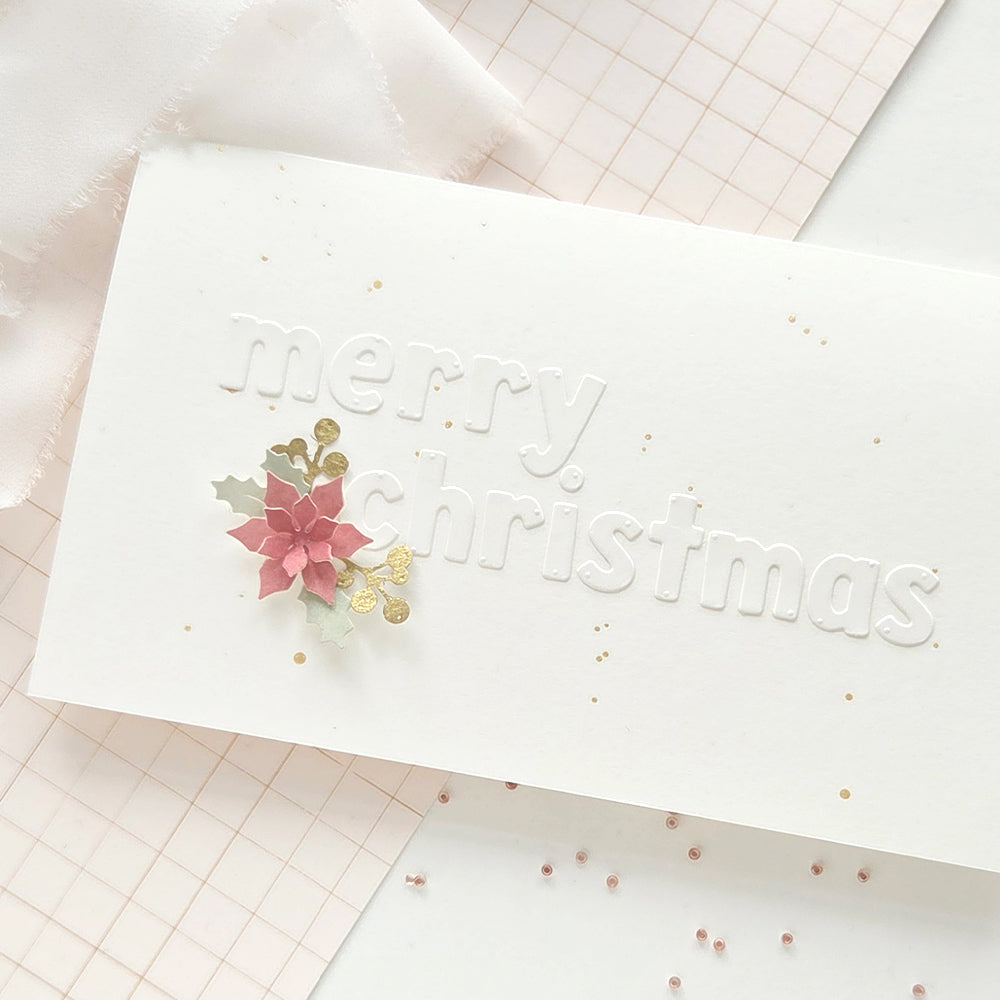 Eine weiße, geprägte Weihnachtskarte, verziert mit einem Weihnachtsstern aus Papier, der mit einer Motivstanze hergestellt wurde.