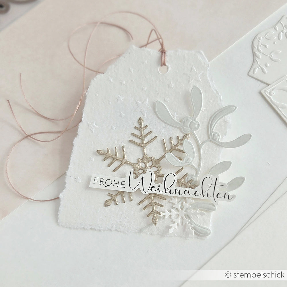 Weißes Geschenkanhängerchen mit einer Schneeflocke, Mistelzweig und der Aufschrift Frohe Weihnachten, hergestellt mit einer Motivstanze.