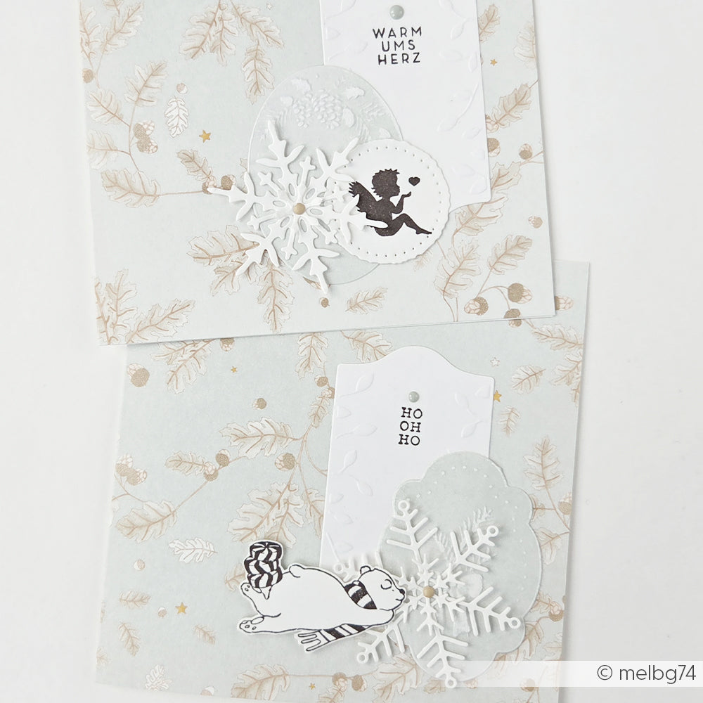 Zwei handgefertigte Weihnachtskarten mit Schneeflocken, der Silhouette eines Engelchens und einem Eisbären.
