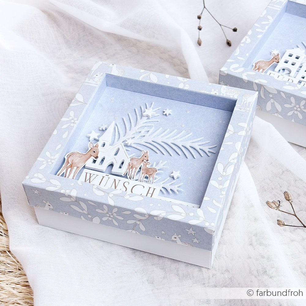 Hellblaue Geschenkbox mit einer Papercraft-Szene Weihnachtsstadt von Motivstanze und dem Schriftzug WÜNSCH.