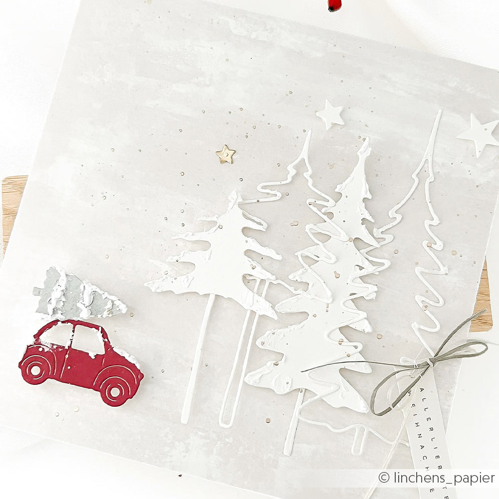 Weihnachtskarte mit einer Winterspaß-Szene: Papierbäume, ein rotes Auto, das einen Baum transportiert, und kleine Sterne.