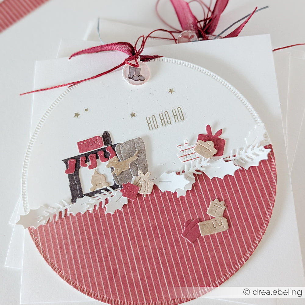 Runde Weihnachtskarte mit einem Kamin, Geschenken und HO HO HO, hergestellt mit einer Motivstanze.