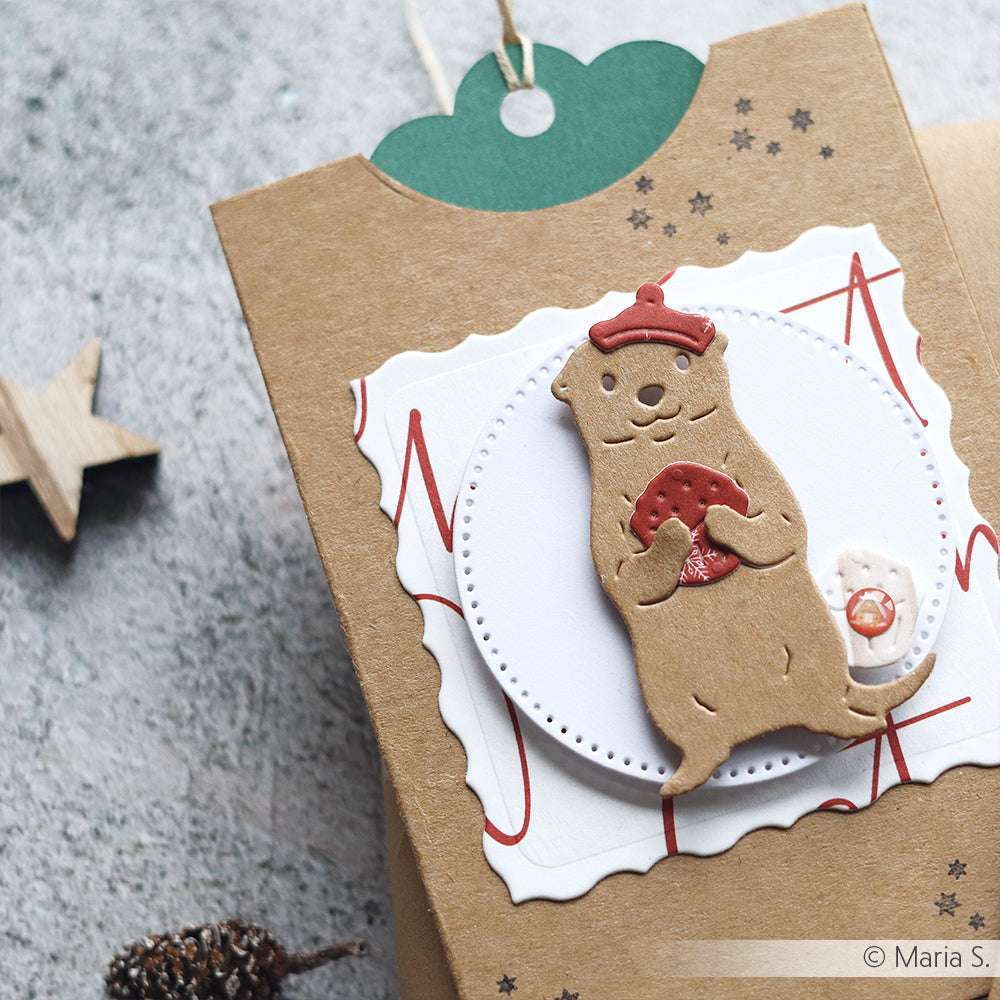 Geschenkkarton von Alexandra Renke, dekoriert mit einem niedlichen Keks in Form eines Otters, der eine rote Muschel auf einem festlichen Anhänger hält und mit einem charmanten Stempelmotiv verziert ist, das für eine ganz besondere Note sorgt.