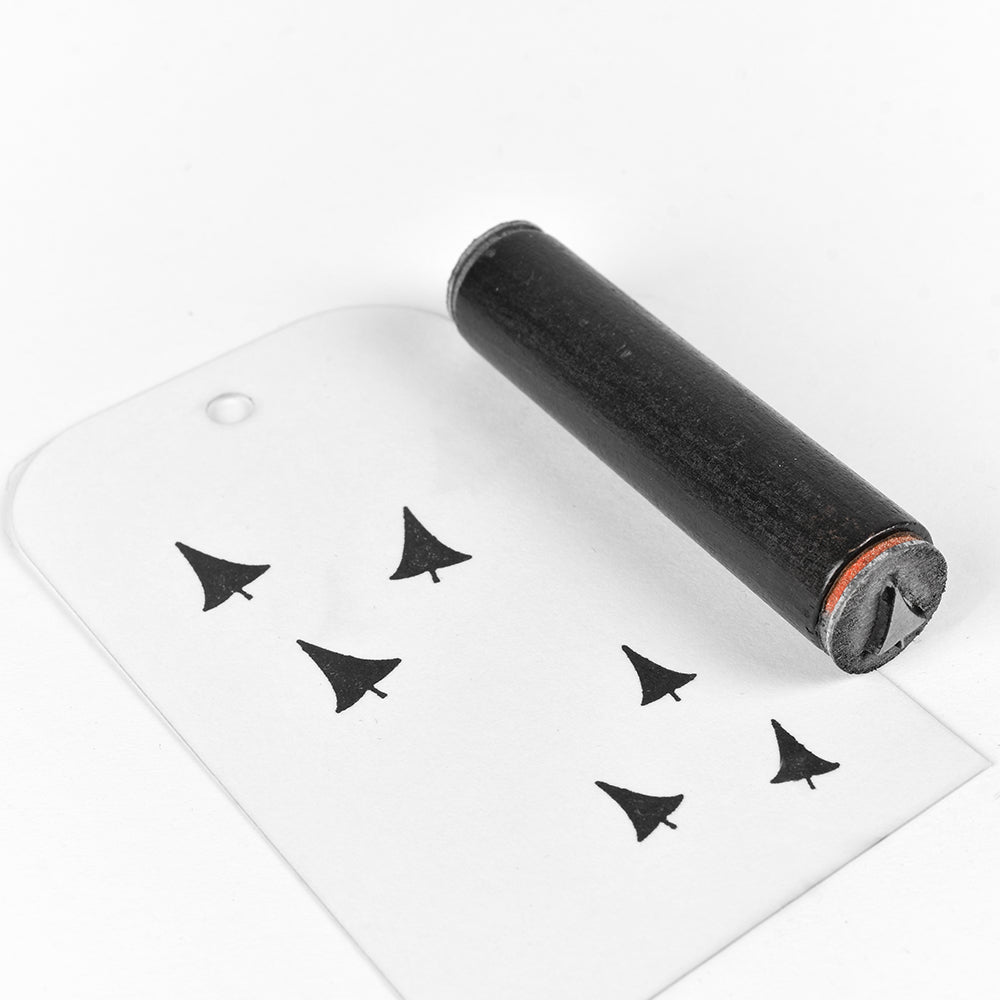 Ein schwarzer Stempel von Alexandra Renke und gestempelte Bilder von kleinen Bäumen auf einem weißen Anhänger mit einem Loch.