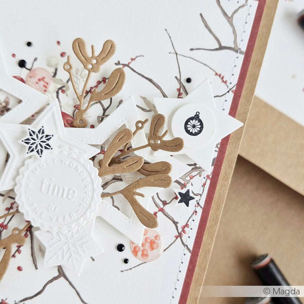 Handgefertigte Winterkarte von Alexandra Renke mit übereinanderliegenden Sternen, gestempelten Zweigen, Geweihverzierungen und zarten Akzenten.