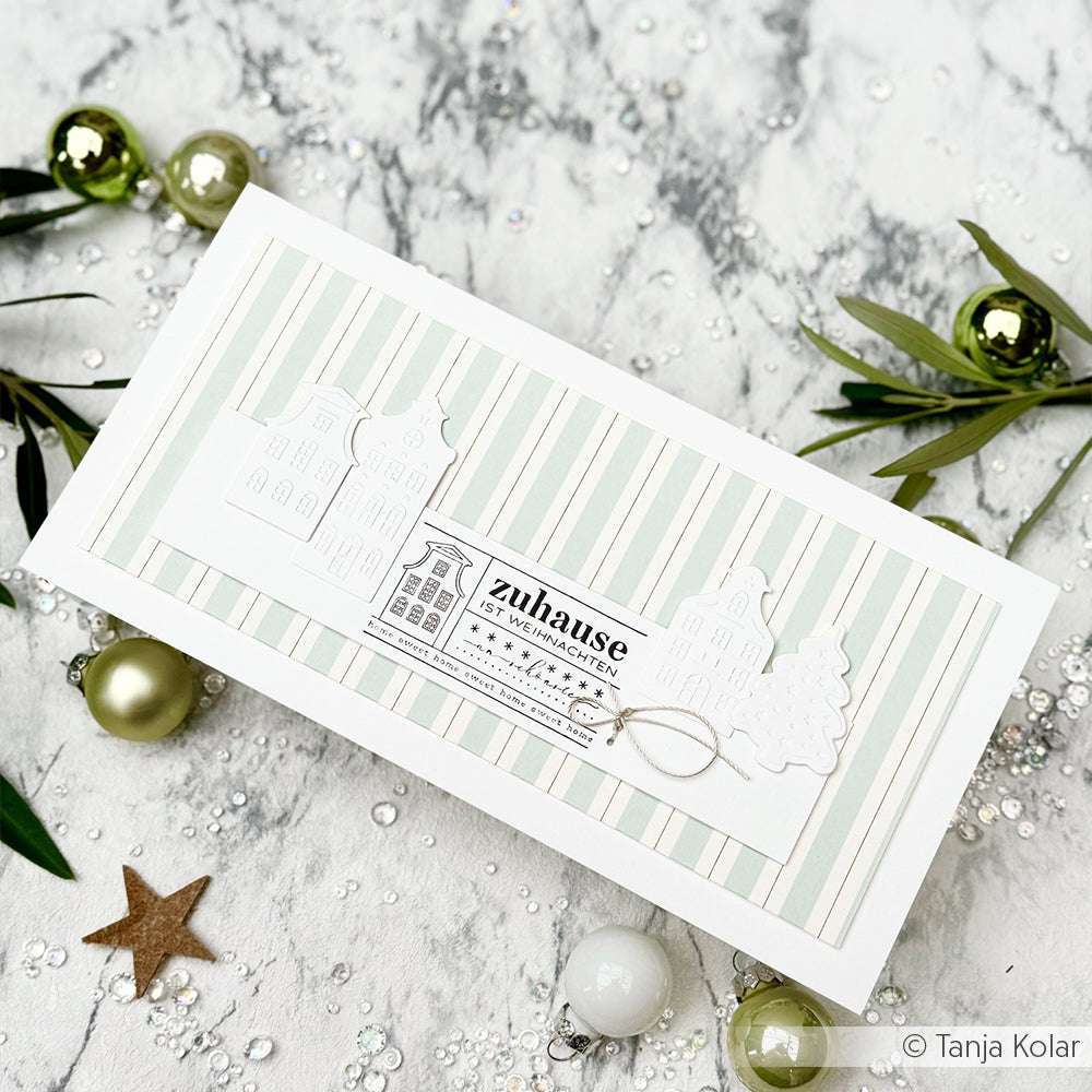Eine handgemachte gestreifte Weihnachtskarte von Alexandra Renke mit weißen Häusern, deutschem Text, festlichen Ornamenten und einzigartigen Akzenten aus hochwertigem Holz und Stempel Weihnachten.
