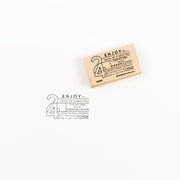 Ein Holzstempel und sein Abdruck mit einem weihnachtlichen Text und der Zahl 24.