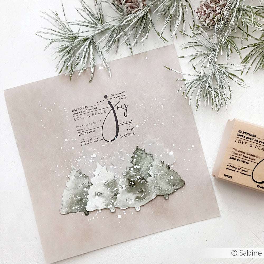 Aquarellbäume mit Schnee und dem Text "Joy to the World", umrahmt von gefrosteten Tannenzweigen auf hellem Hintergrund - eine ideale Inspiration für Papierprojekte mit Alexandra Renke Holzstempel oder Stempelgummi-Designs.