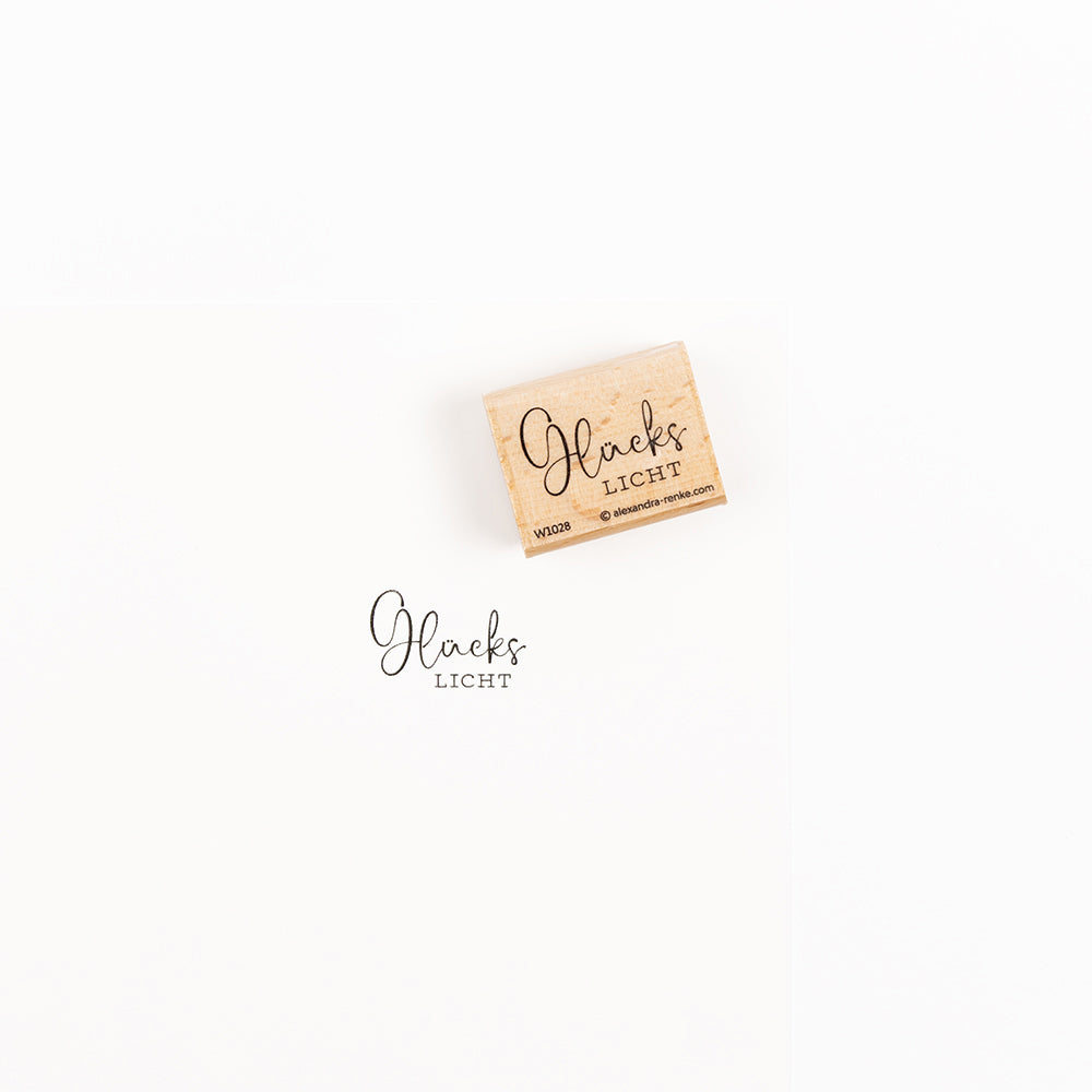 Ein Glückslicht-Stempel aus Holz und sein Abdruck auf Papier.