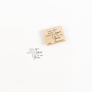 Ein Holzstempel und sein Abdruck mit detailreichen Motiven, auf denen der Feiertagstext zu lesen ist.